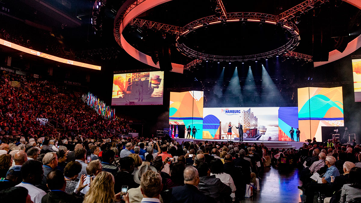 In a big indoor arena, a Rotary International general session is in progress.